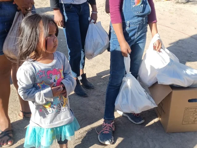 A young girl waits with her family to receive food.