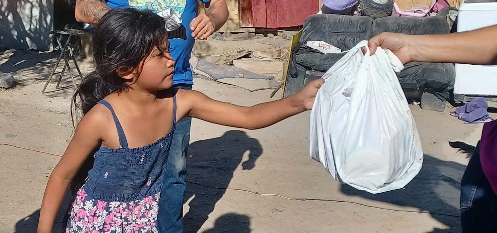 Volunteers handing a bag of food to a child